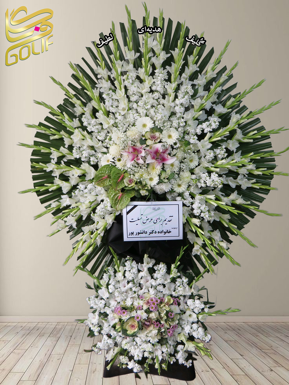 تاج گل تسلیت یک و نیم طبقه (گلایل، داوودی) تاج گل ختم، تاج گل ترحیم، تاج گل مراسم ترحیم گل‌های غالب این تاج گل عبارتند از: گلایل‌های سفید: که در قسمت‌های مختلف به چشم می‌خورند و جلوه‌ای شیک و ساده ایجاد کرده‌اند. داوودی‌های سفید: این گل‌ها به‌طور پراکنده استفاده شده و باعث افزایش حجم و جذابیت طراحی شده‌اند. همچنین برگ‌های سبز به عنوان پس‌زمینه، ترکیب گل‌ها را بیشتر برجسته کرده‌اند. امیدوارم این اطلاعات مفید باشد!. سفارش آنلاین تاج گل سفارش آنلاین گل عکاسی شده توسط گل‌فروشی آنلاین گلیف